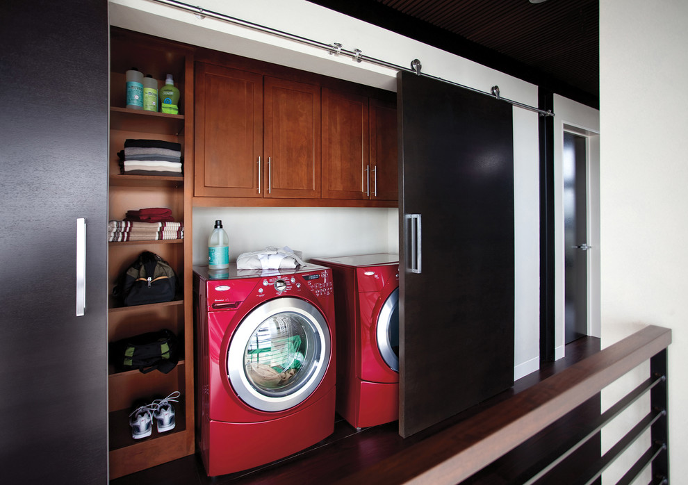 Transitional single-wall laundry cupboard in Other with recessed-panel cabinets, white walls, dark hardwood floors, a side-by-side washer and dryer, brown floor and dark wood cabinets.