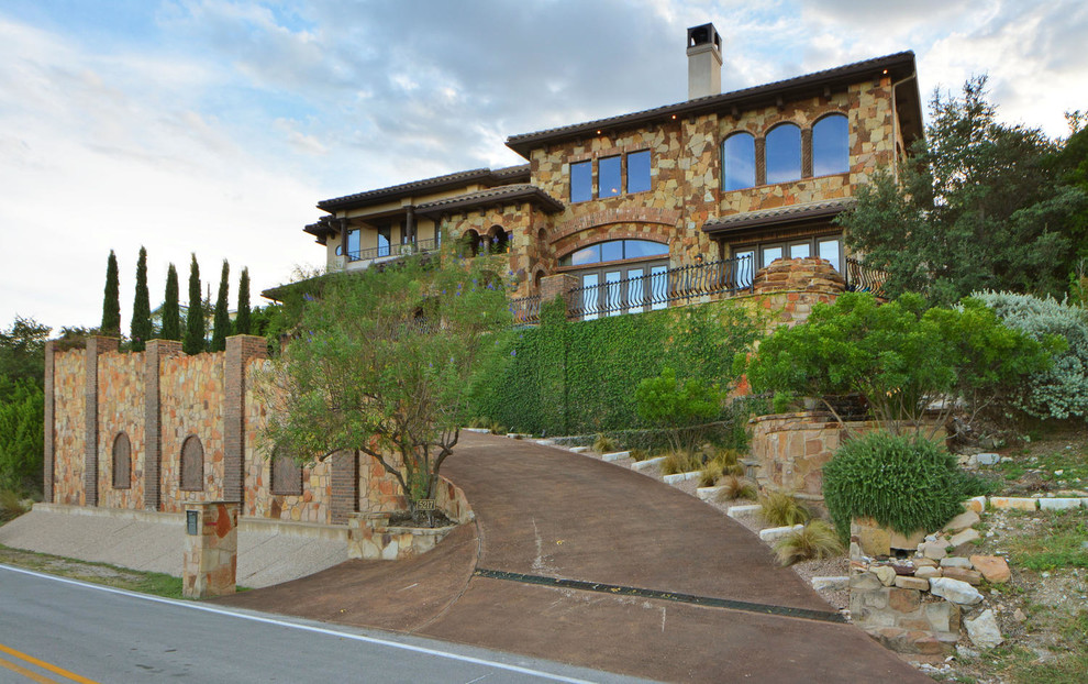 Photo of an expansive mediterranean two-storey beige exterior in Austin with stone veneer.