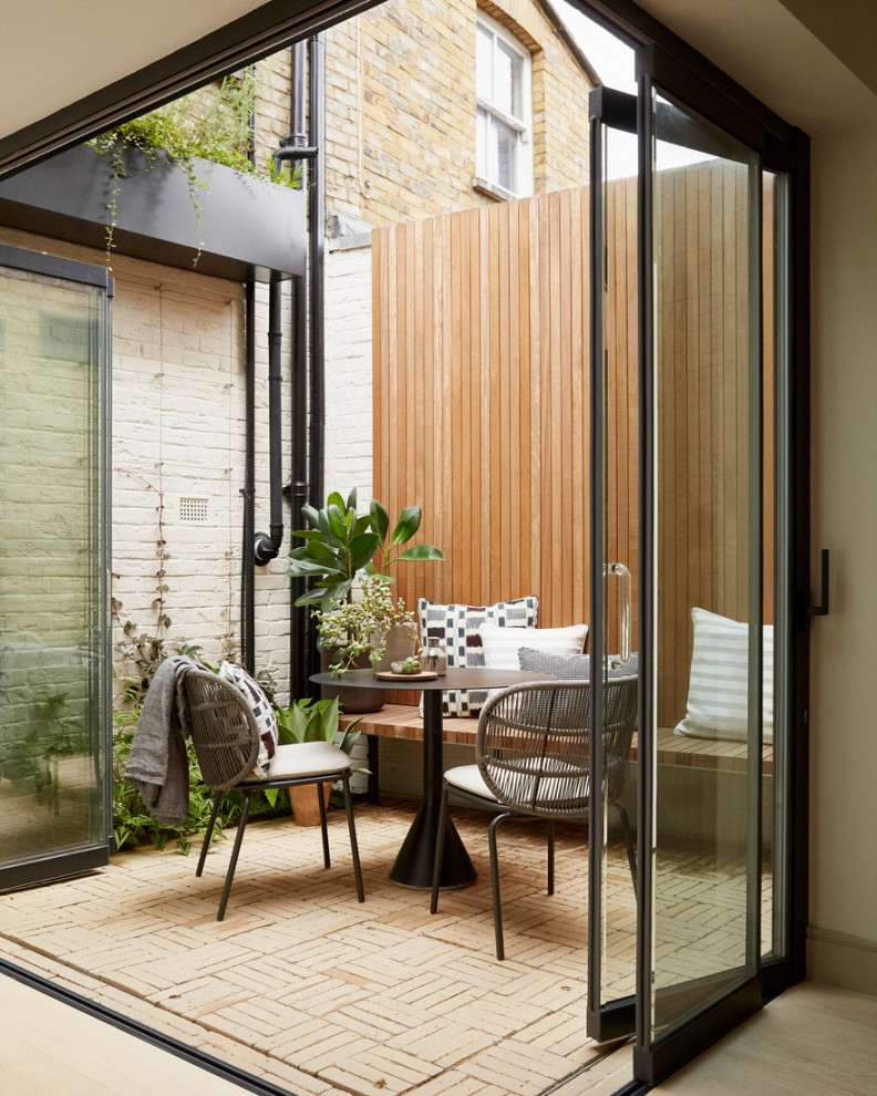 Inspiration for a small contemporary courtyard partial sun formal garden for fall in London with with path, brick pavers and a wood fence.