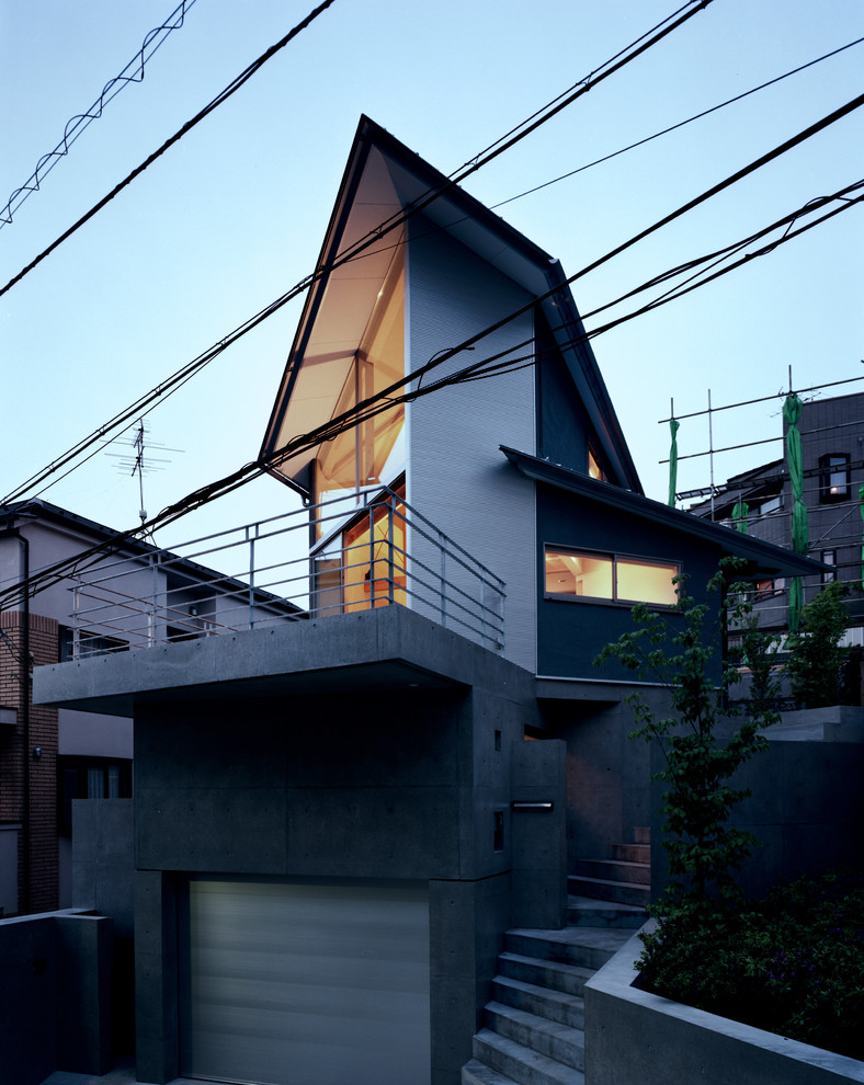 Mid-sized asian three-storey grey house exterior in Tokyo with metal siding, a gable roof and a metal roof.