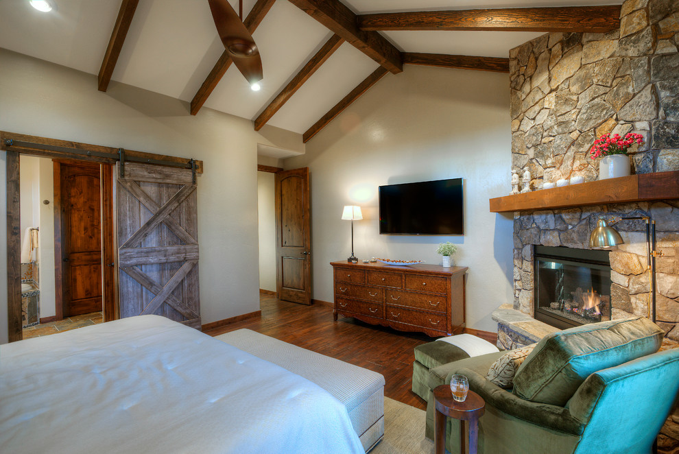 Inspiration for a master bedroom in Phoenix with dark hardwood floors, a corner fireplace and a stone fireplace surround.