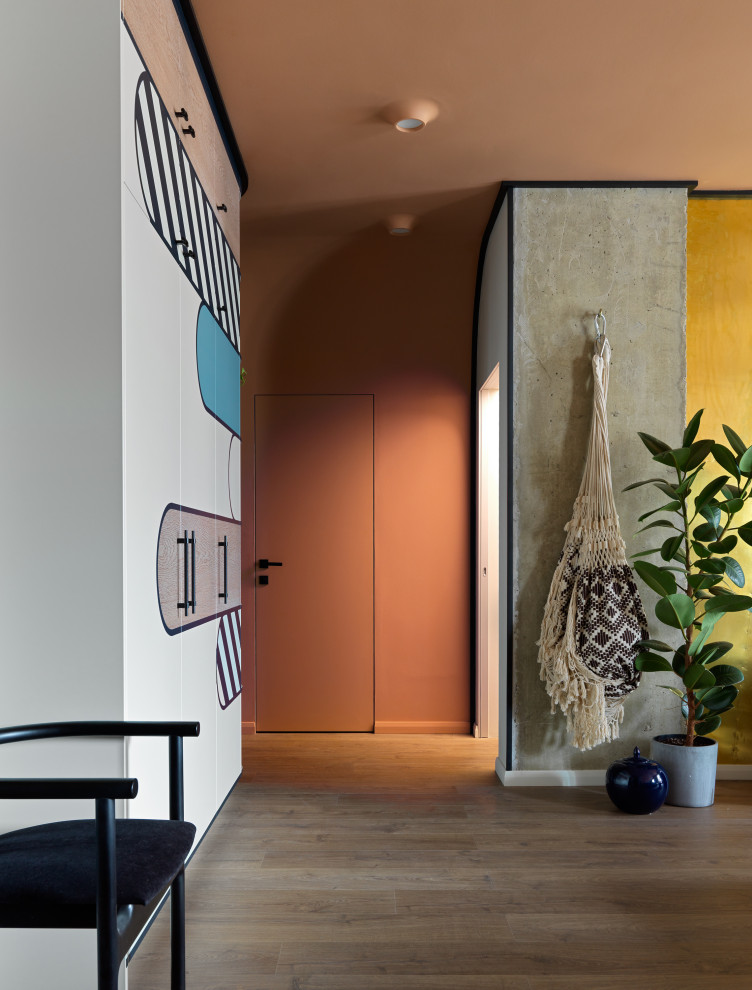 Ispirazione per un soggiorno boho chic di medie dimensioni con sala formale, pareti multicolore, pavimento in laminato, TV a parete e pavimento marrone