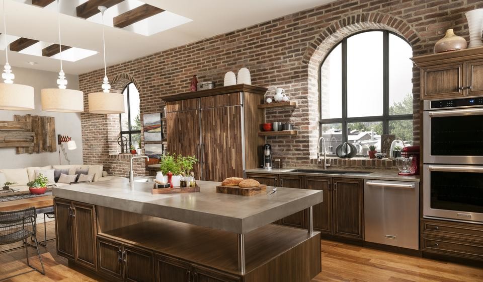 Example of a large transitional l-shaped medium tone wood floor and brown floor eat-in kitchen design with stainless steel appliances, an island, an undermount sink, beaded inset cabinets, medium tone wood cabinets, stainless steel countertops, brown backsplash and brick backsplash