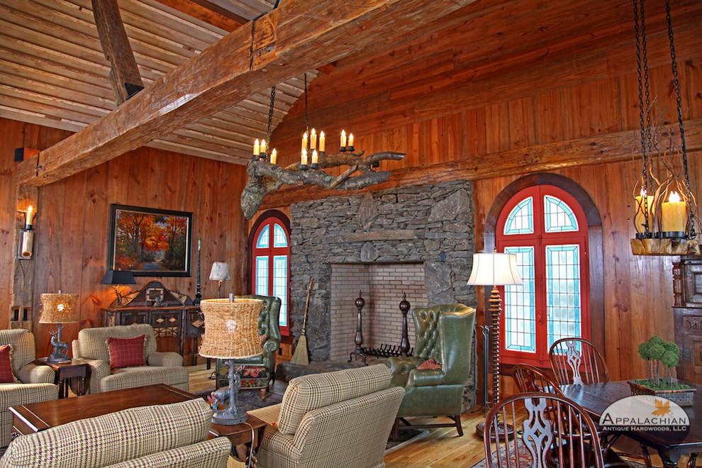 Photo of a mid-sized country open concept living room in Other with a home bar, brown walls, medium hardwood floors, a standard fireplace, a stone fireplace surround and brown floor.