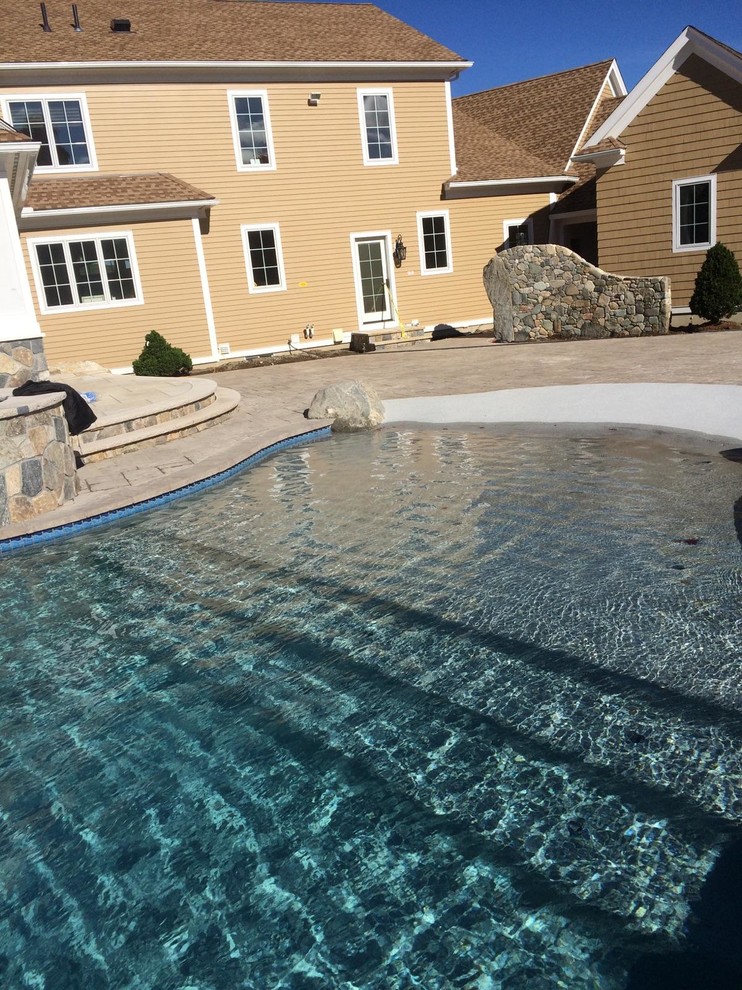 Large backyard stone and custom-shaped lap hot tub photo in Boston