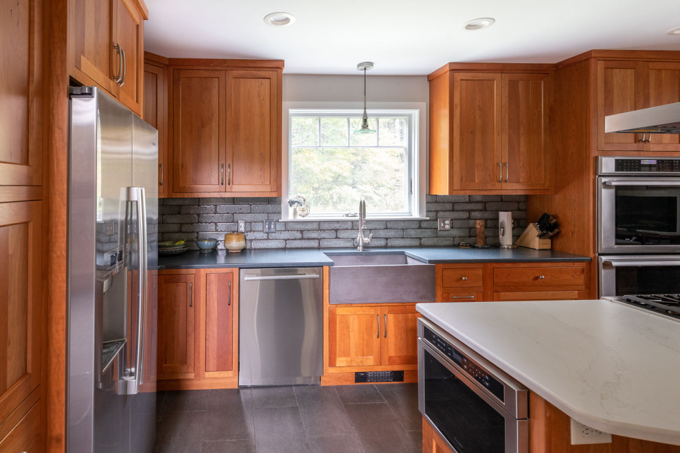 Eat-in kitchen - large transitional l-shaped porcelain tile and gray floor eat-in kitchen idea in Boston with a farmhouse sink, shaker cabinets, medium tone wood cabinets, quartz countertops, gray backsplash, porcelain backsplash, stainless steel appliances, an island and white countertops