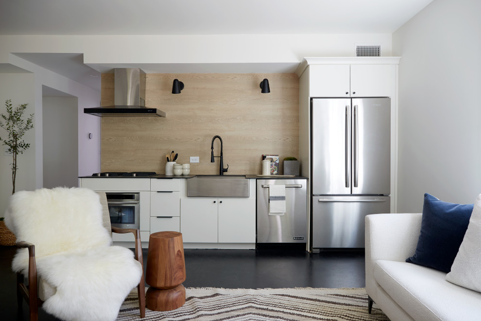 Inspiration for a contemporary single-wall black floor open concept kitchen remodel in Austin with flat-panel cabinets, white cabinets, laminate countertops, beige backsplash, wood backsplash, no island, black countertops, a farmhouse sink and stainless steel appliances