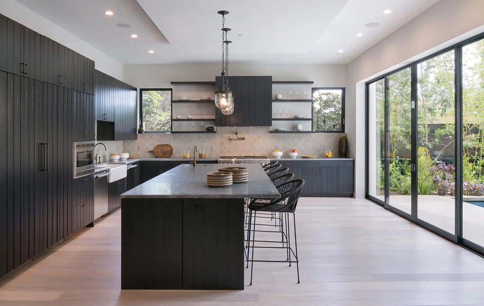 Design ideas for a large contemporary l-shaped open plan kitchen in Los Angeles with a farmhouse sink, dark wood cabinets, marble benchtops, beige splashback, ceramic splashback, stainless steel appliances, porcelain floors, with island, beige floor, grey benchtop and flat-panel cabinets.