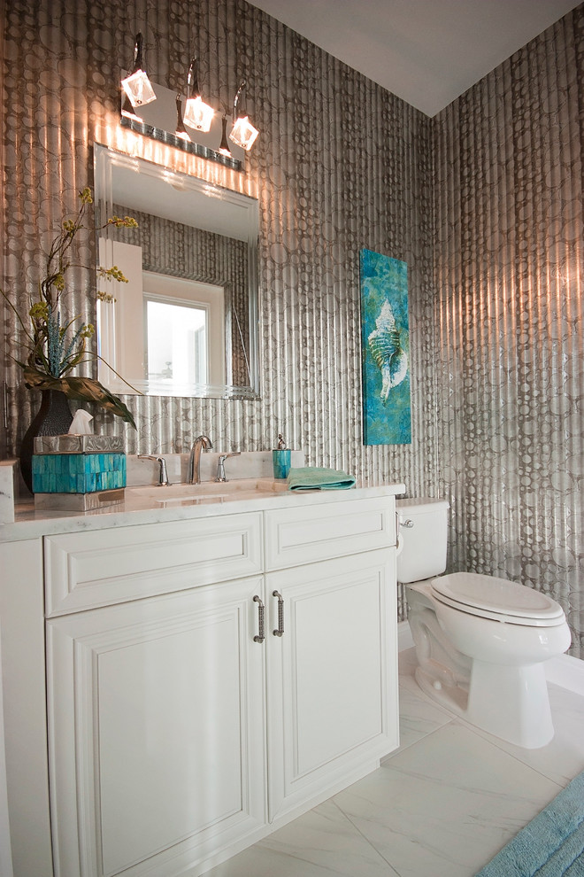 Inspiration for a beach style powder room in Miami with an undermount sink, raised-panel cabinets, white cabinets, marble benchtops, a two-piece toilet, grey walls and marble floors.
