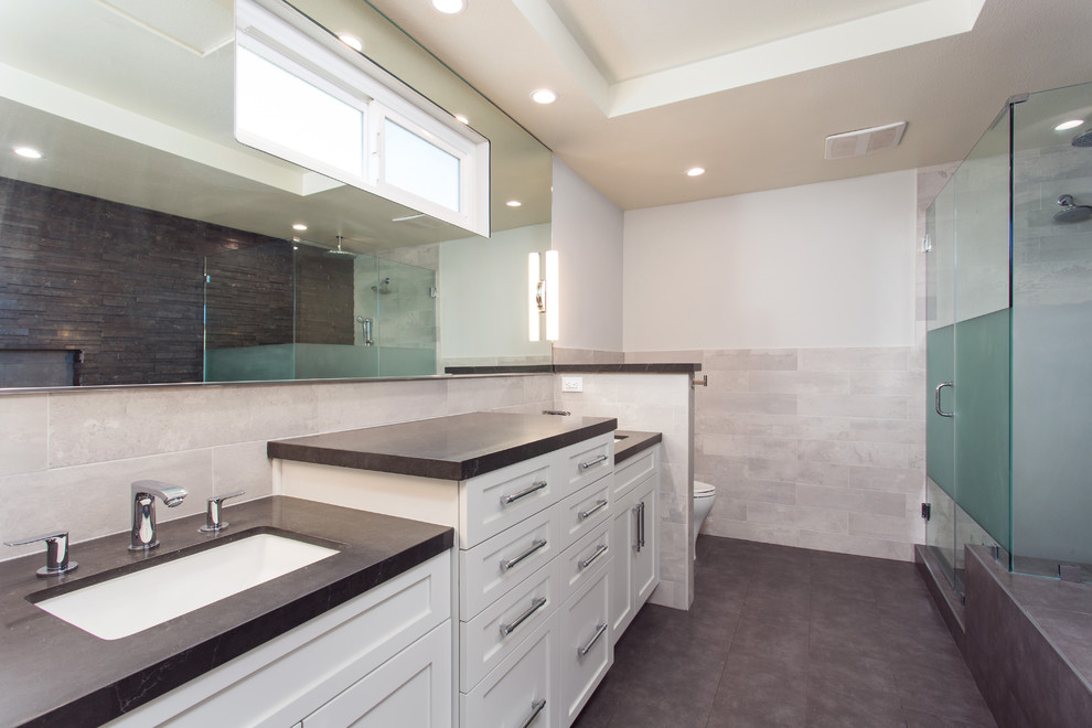 Large transitional master bathroom in Los Angeles with shaker cabinets, white cabinets, a hot tub, a corner shower, a two-piece toilet, black tile, slate, grey walls, ceramic floors, an undermount sink, engineered quartz benchtops, black floor and a hinged shower door.