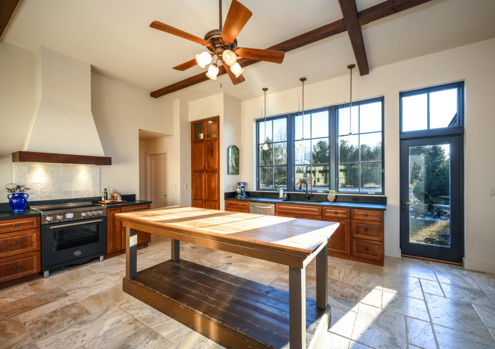 Example of a huge mountain style u-shaped travertine floor, beige floor and exposed beam eat-in kitchen design with an undermount sink, medium tone wood cabinets, soapstone countertops, black backsplash, stainless steel appliances, no island and black countertops