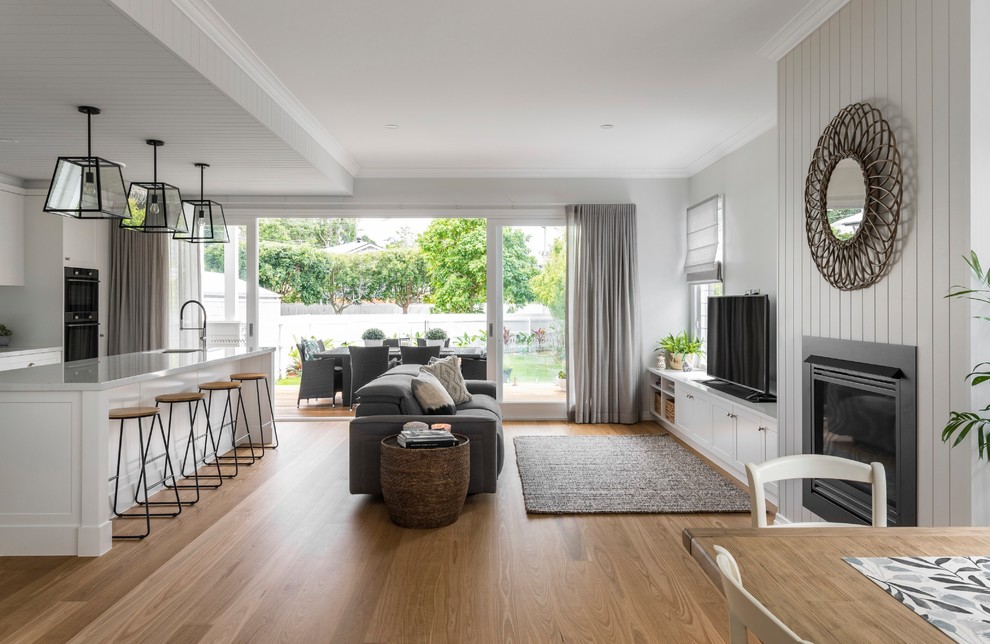 Transitional open concept living room in Brisbane with grey walls, medium hardwood floors, a standard fireplace, a freestanding tv and brown floor.