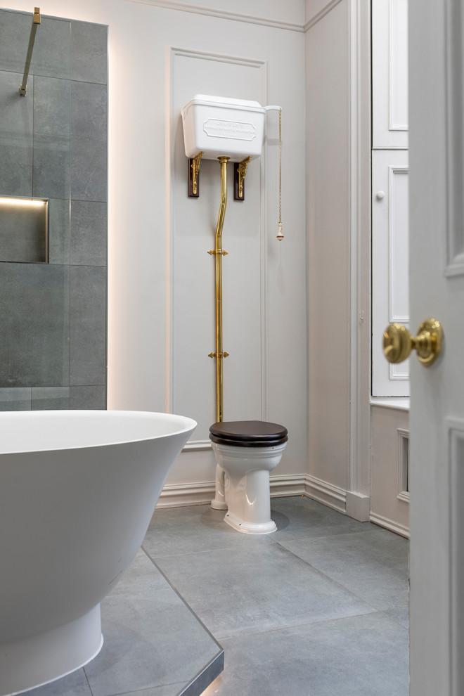This is an example of a large eclectic kids bathroom in Edinburgh with a freestanding tub, an open shower, a two-piece toilet, gray tile, porcelain tile, white walls, porcelain floors, grey floor, an open shower and panelled walls.