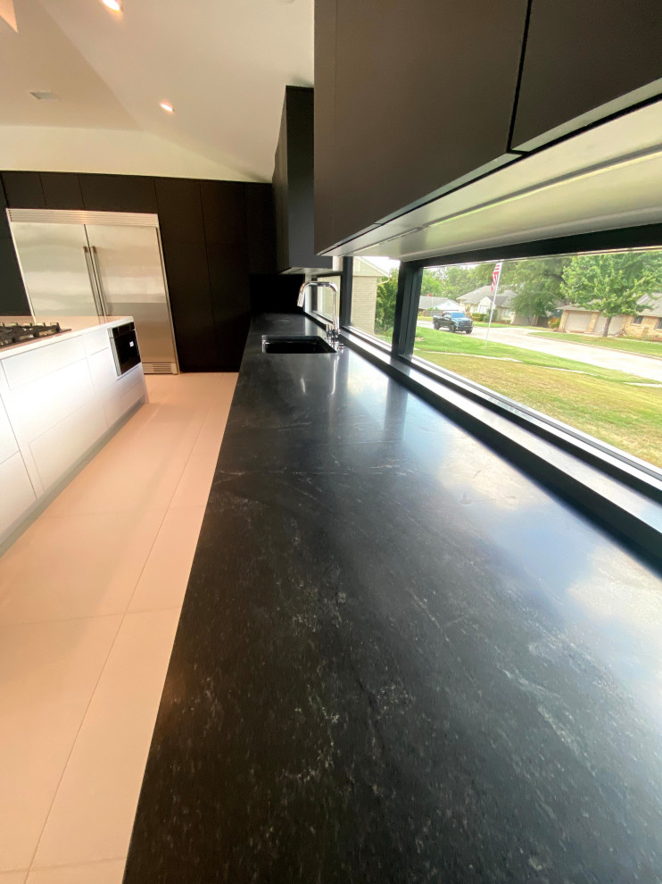 Idéer för ett modernt svart linjärt kök med öppen planlösning, med en dubbel diskho, släta luckor, vita skåp, bänkskiva i onyx, svart stänkskydd, fönster som stänkskydd, rostfria vitvaror, klinkergolv i porslin, en köksö och vitt golv