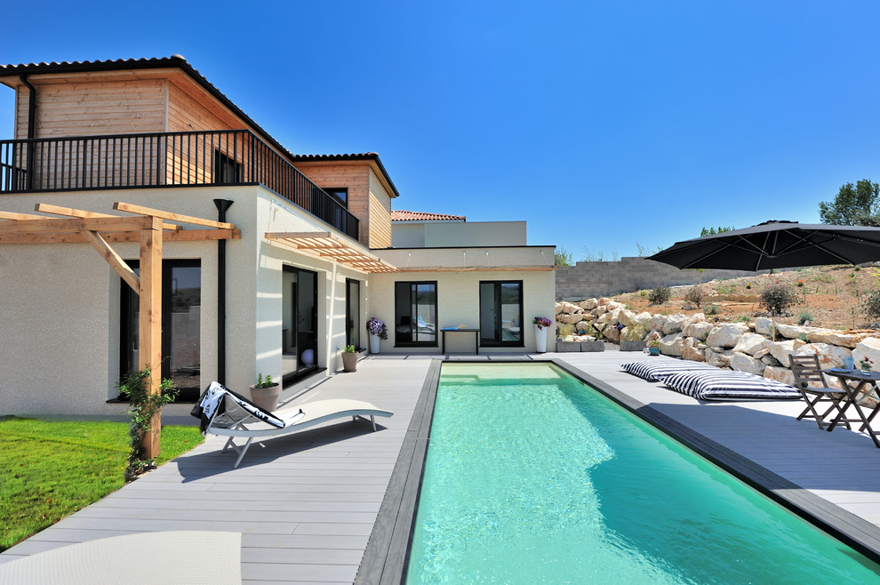 Large contemporary backyard rectangular lap pool in Montpellier with decking.