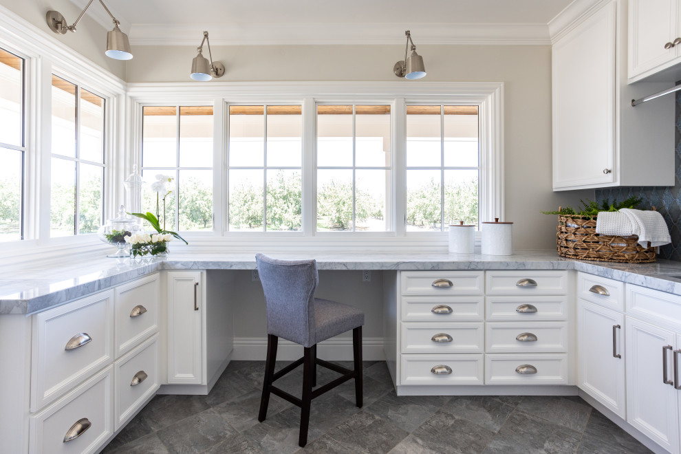 Inspiration for a small beach style u-shaped utility room in Sacramento with an undermount sink, recessed-panel cabinets, white cabinets, quartzite benchtops, blue splashback, porcelain splashback, grey walls, ceramic floors, a stacked washer and dryer, grey floor, grey benchtop and wood.