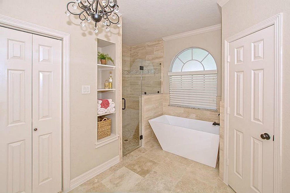 This is an example of a mid-sized traditional master bathroom in Houston with recessed-panel cabinets, white cabinets, a freestanding tub, a corner shower, beige tile, travertine, beige walls, travertine floors, an undermount sink, granite benchtops, beige floor and a hinged shower door.