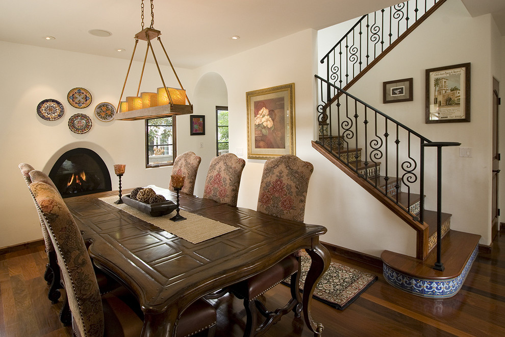 Photo of a traditional dining room in Los Angeles with white walls, dark hardwood floors and a ribbon fireplace.