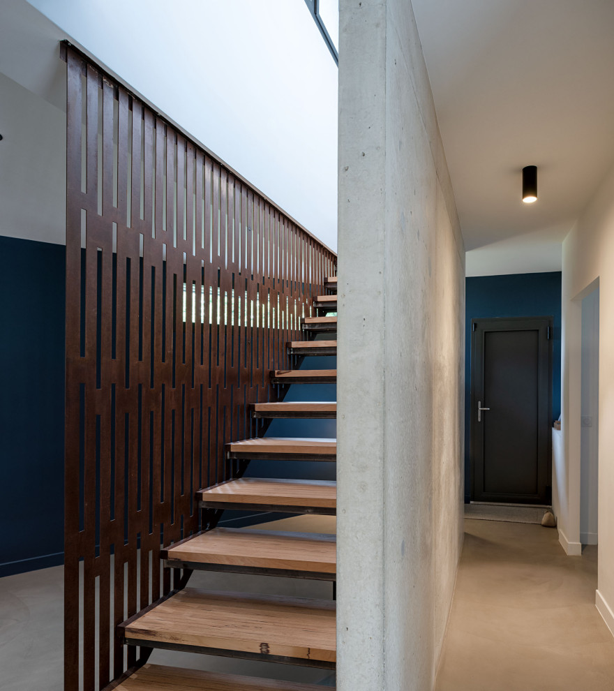 Cette image montre un escalier sans contremarche droit design de taille moyenne avec des marches en bois, un garde-corps en métal, un mur en parement de brique et rangements.