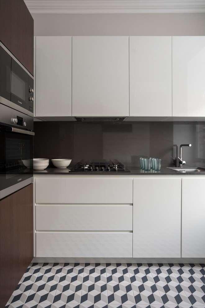 Design ideas for a contemporary l-shaped separate kitchen in Moscow with an undermount sink, flat-panel cabinets, white cabinets, grey splashback, stainless steel appliances, multi-coloured floor and grey benchtop.