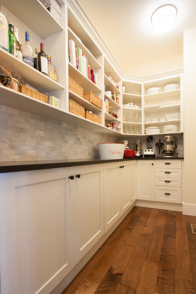 This is an example of a large traditional l-shaped kitchen pantry in Vancouver with a drop-in sink, shaker cabinets, white cabinets, concrete benchtops, grey splashback, stone tile splashback, stainless steel appliances, dark hardwood floors, no island and brown floor.