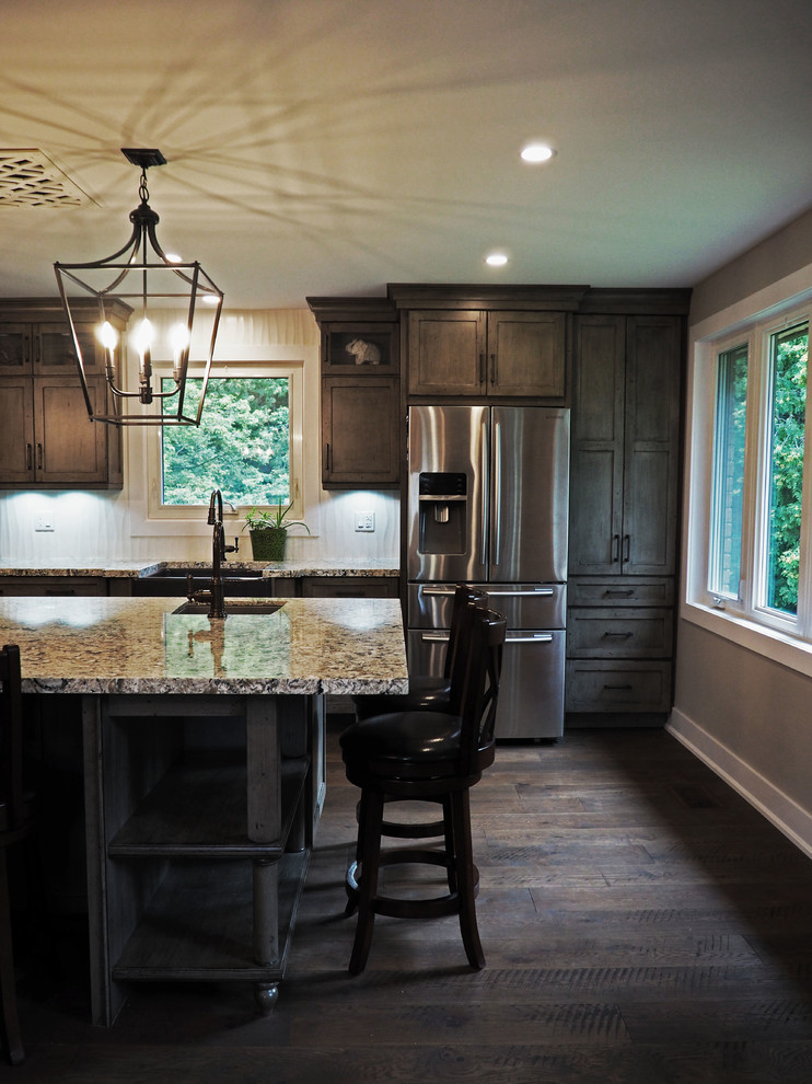 Design ideas for a mid-sized country single-wall eat-in kitchen in Toronto with a farmhouse sink, recessed-panel cabinets, dark wood cabinets, granite benchtops, white splashback, stainless steel appliances, dark hardwood floors, with island and brown floor.