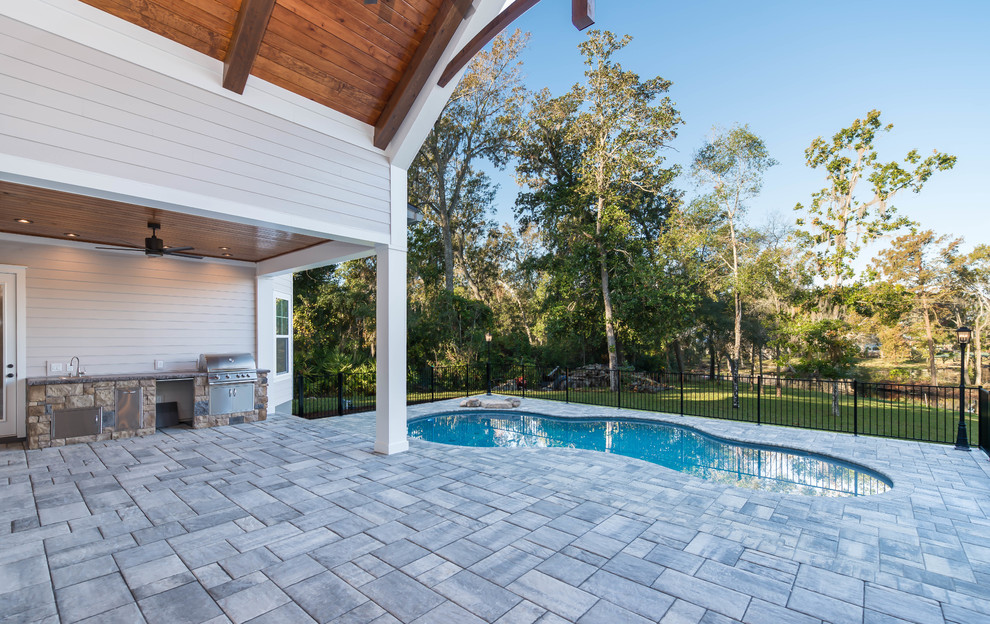 This is an example of a large beach style backyard patio in Jacksonville with an outdoor kitchen, concrete pavers and a roof extension.