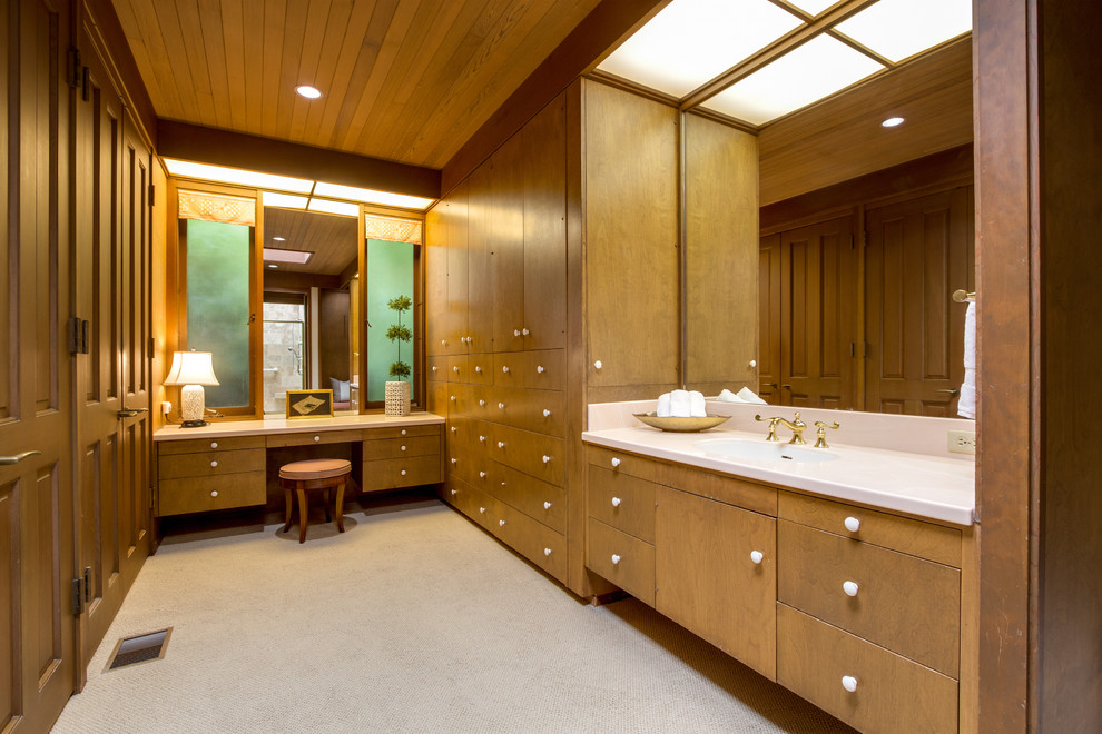 Photo of an expansive midcentury gender-neutral dressing room in Seattle with flat-panel cabinets, medium wood cabinets, carpet and beige floor.