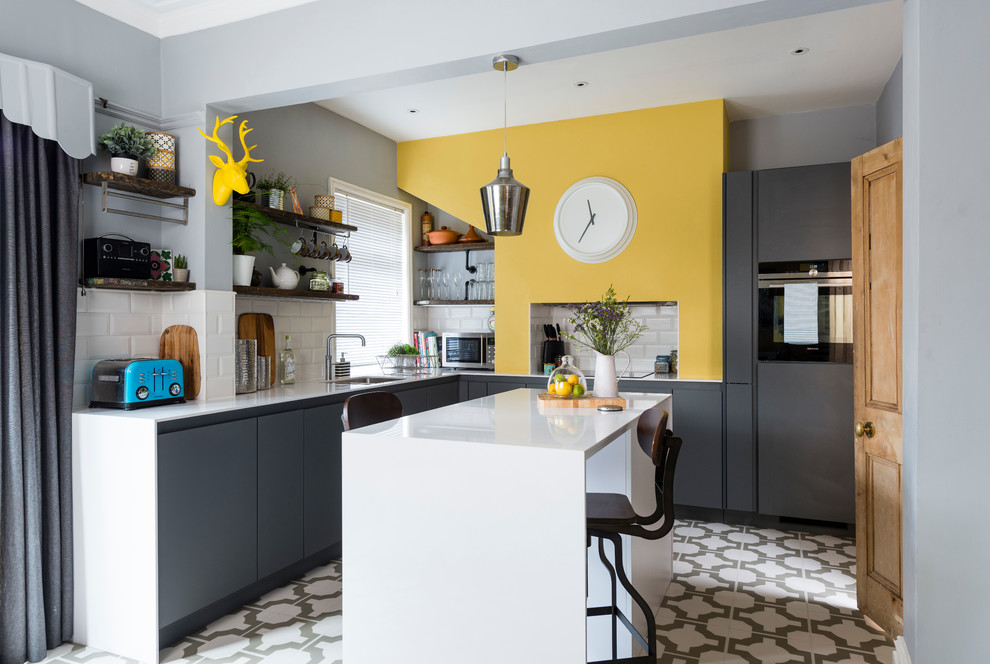 Mid-sized eclectic l-shaped eat-in kitchen in Other with an undermount sink, flat-panel cabinets, grey cabinets, quartzite benchtops, white splashback, ceramic splashback, vinyl floors, with island, white floor, white benchtop, stainless steel appliances and coffered.