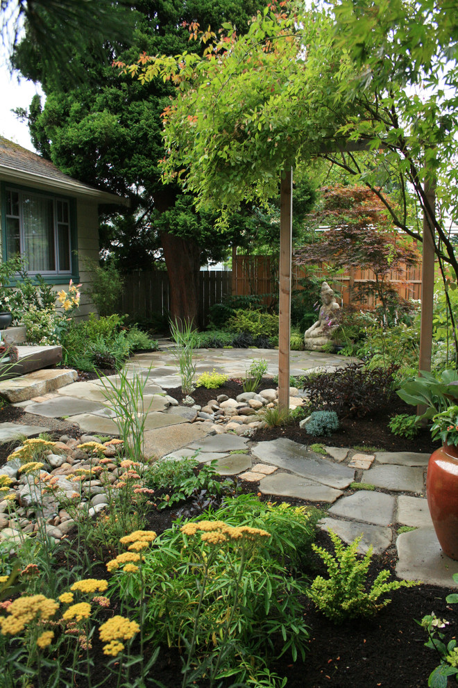 This is an example of an asian partial sun garden in Seattle with natural stone pavers.