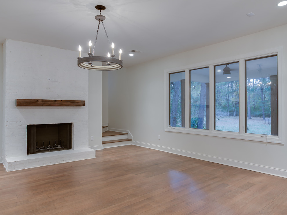 Mid-sized transitional enclosed family room in Other with white walls, light hardwood floors, a standard fireplace, a brick fireplace surround and no tv.
