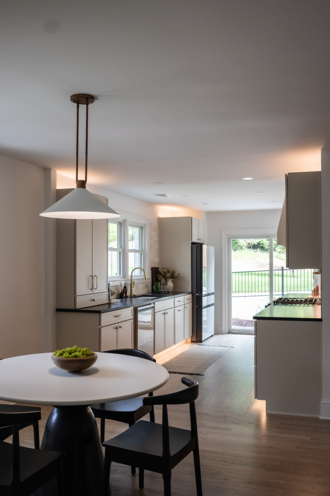 Transitional galley light wood floor and brown floor eat-in kitchen photo in Atlanta with an undermount sink, shaker cabinets, beige cabinets, granite countertops, beige backsplash and black countertops