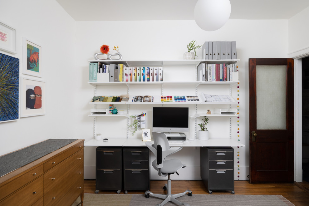 This is an example of a mid-sized transitional home office in Chicago with white walls, a freestanding desk, brown floor and medium hardwood floors.