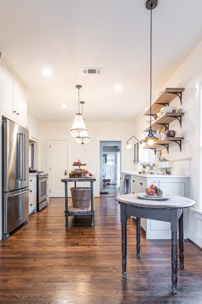 This is an example of a mid-sized arts and crafts galley eat-in kitchen in Other with grey cabinets, with island, white splashback, subway tile splashback, stainless steel appliances, dark hardwood floors and white benchtop.