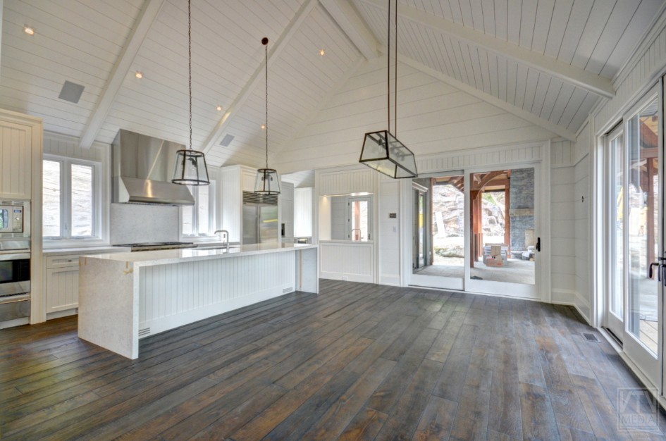 Mid-sized mountain style brown floor eat-in kitchen photo in Toronto with white cabinets, stainless steel appliances and an island