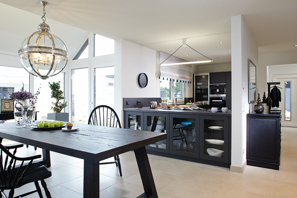 Offene Moderne Küche in U-Form mit grauen Schränken, Küchenrückwand in Grau, schwarzen Elektrogeräten, Halbinsel, grauer Arbeitsplatte, Terrakottaboden und beigem Boden in Sonstige