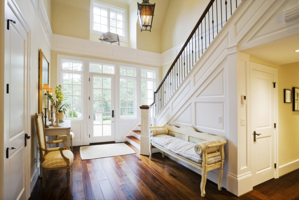 Photo of a large traditional entry hall in Denver with yellow walls, dark hardwood floors, a single front door, a glass front door and brown floor.