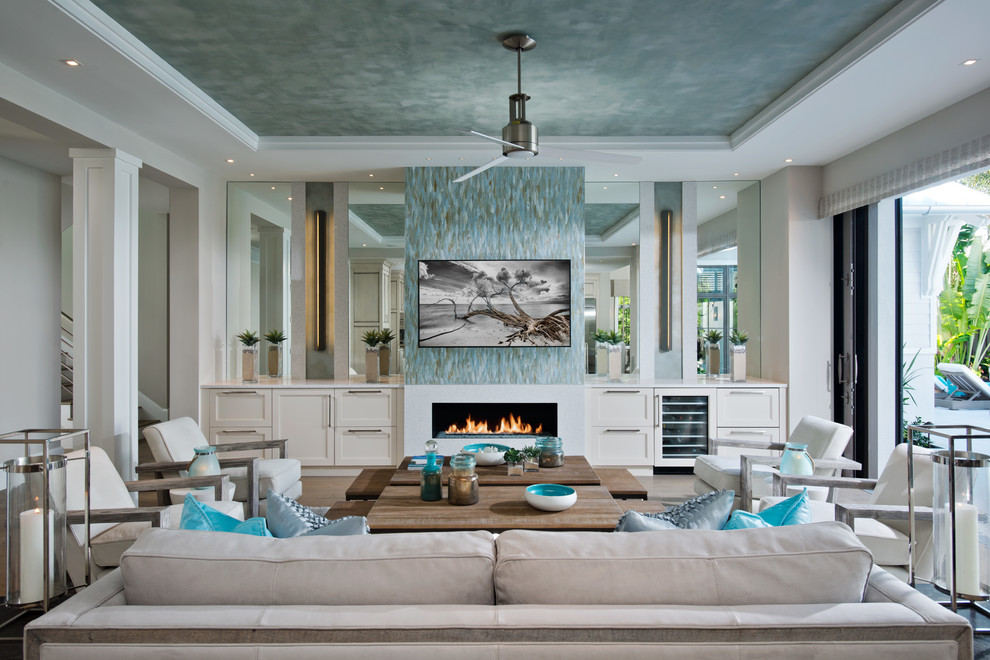 Photo of a large beach style open concept living room in New York with a music area, white walls, light hardwood floors, a standard fireplace, a plaster fireplace surround and no tv.