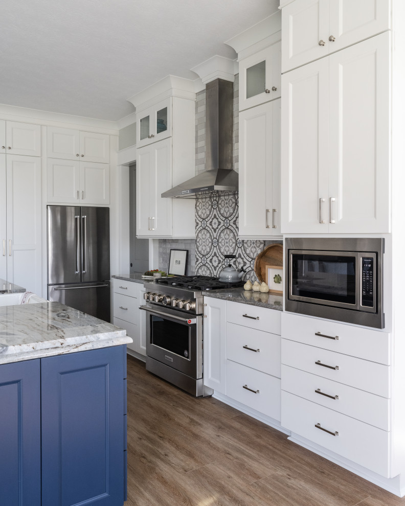 Bild på ett mellanstort funkis kök, med en undermonterad diskho, luckor med glaspanel, blå skåp, granitbänkskiva, vitt stänkskydd, rostfria vitvaror, mellanmörkt trägolv och en köksö