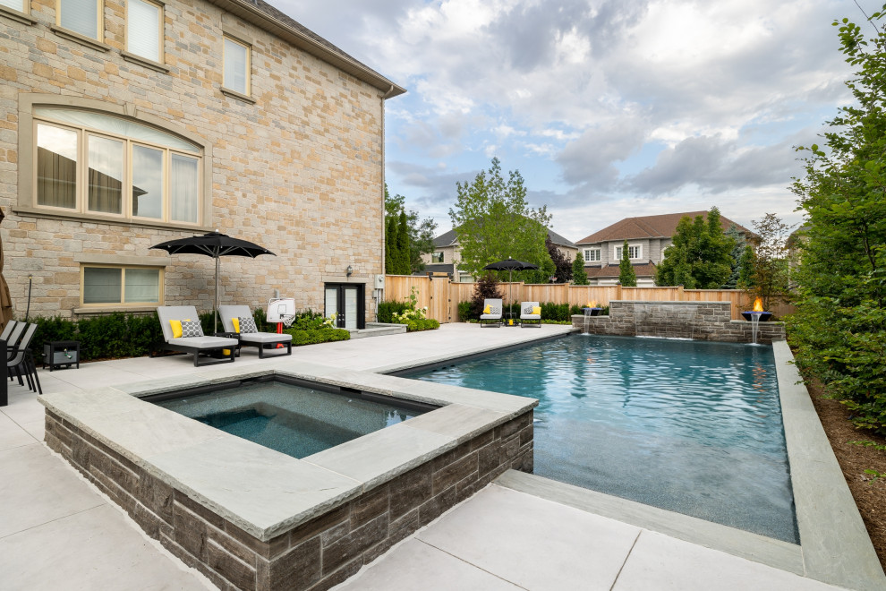 Photo of a medium sized classic back rectangular swimming pool in Toronto with with pool landscaping and stamped concrete.