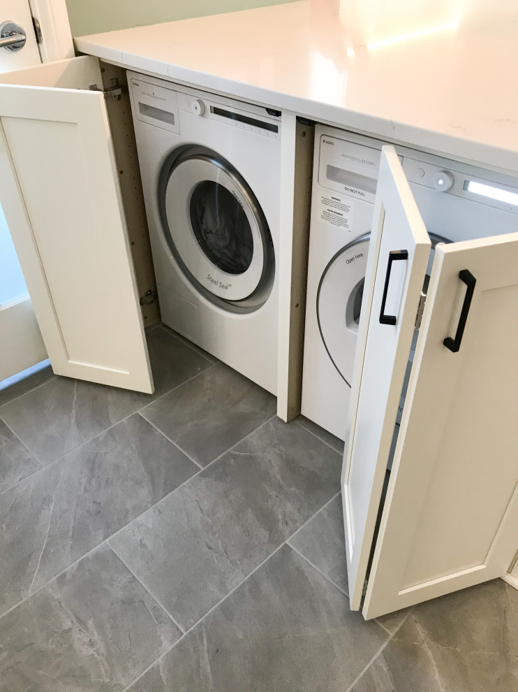Design ideas for a mid-sized transitional l-shaped laundry room in Chicago with an undermount sink, shaker cabinets, white cabinets, blue splashback, glass sheet splashback, porcelain floors, grey floor and white benchtop.
