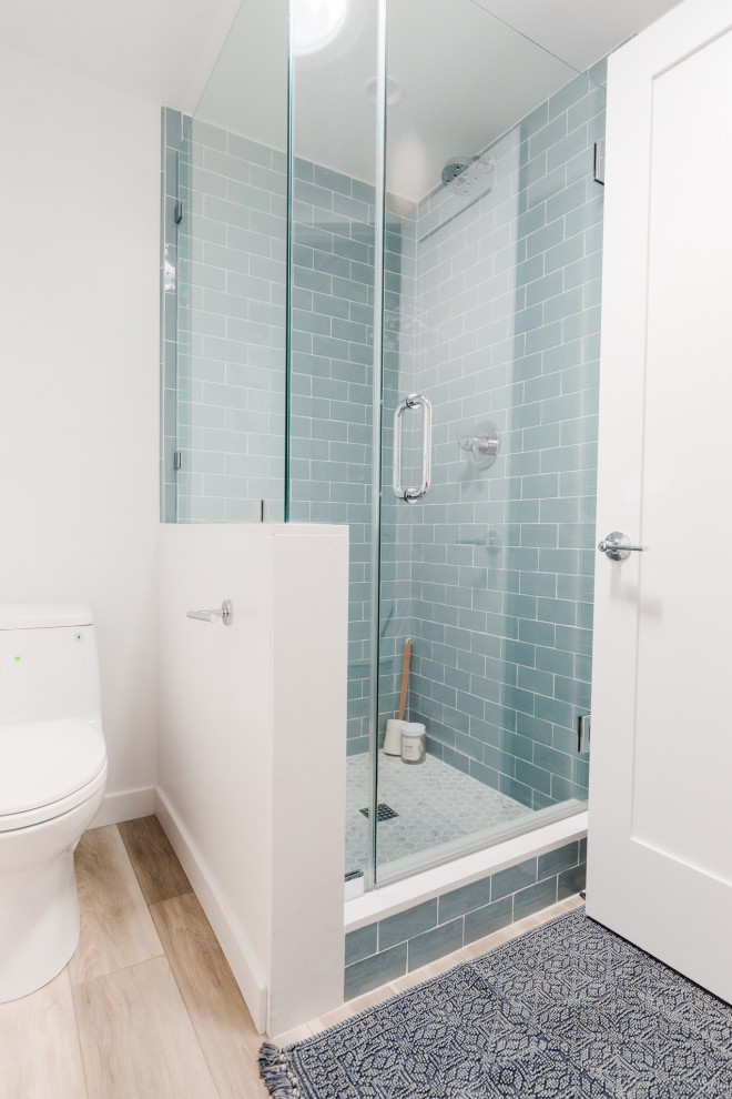 Cette image montre une salle de bain marine avec un lavabo encastré, une douche d'angle, WC à poser, un carrelage bleu, une cabine de douche à porte battante et un carrelage métro.