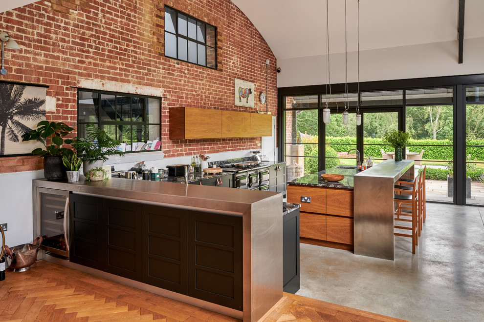 Inspiration for a mid-sized contemporary open plan kitchen in Hampshire with flat-panel cabinets, medium wood cabinets, marble benchtops, concrete floors, multiple islands, grey floor and black benchtop.