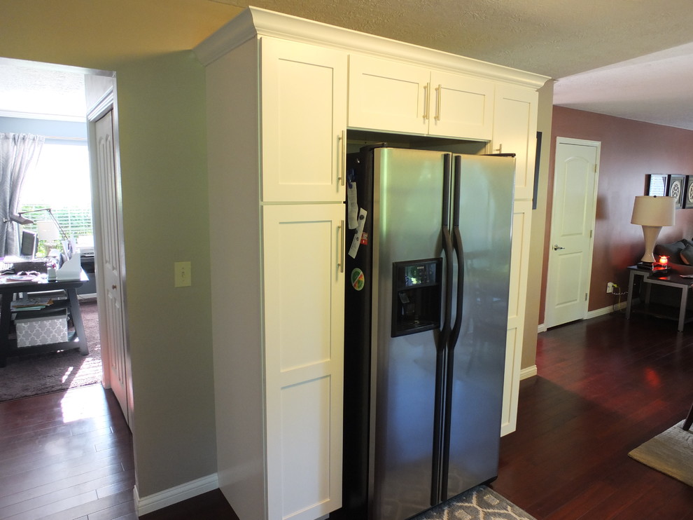Example of a mid-sized trendy l-shaped dark wood floor enclosed kitchen design in Columbus with an undermount sink, shaker cabinets, yellow cabinets, granite countertops, beige backsplash, stainless steel appliances and no island