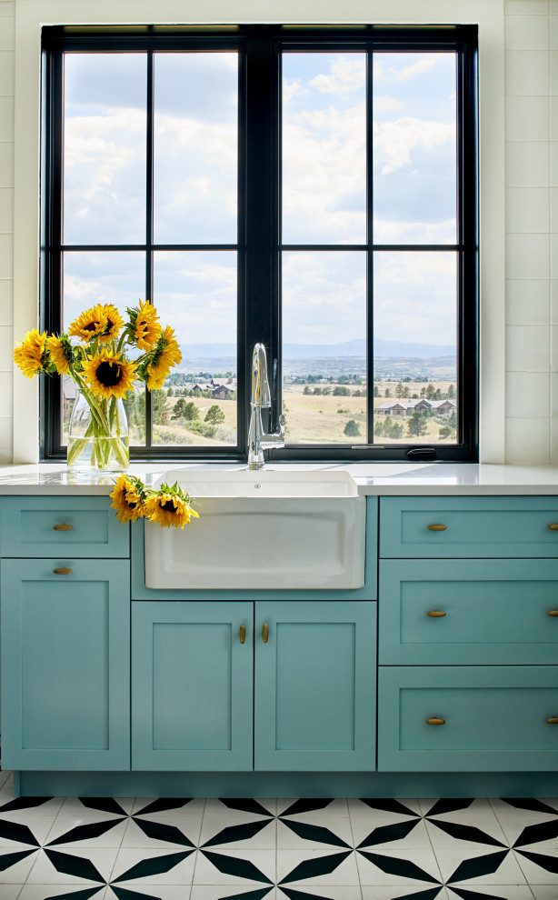 Photo of a large country dedicated laundry room in Denver with a farmhouse sink, shaker cabinets, turquoise cabinets, white walls, multi-coloured floor and white benchtop.