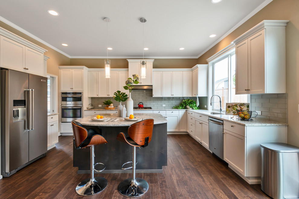 Inspiration for a transitional u-shaped kitchen in Seattle with an undermount sink, shaker cabinets, white cabinets, grey splashback, glass tile splashback, stainless steel appliances, dark hardwood floors, with island, brown floor and beige benchtop.