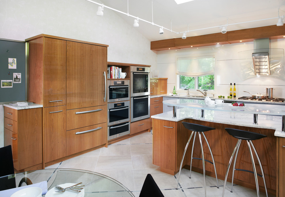 This is an example of a contemporary l-shaped eat-in kitchen in New York with flat-panel cabinets, medium wood cabinets and panelled appliances.