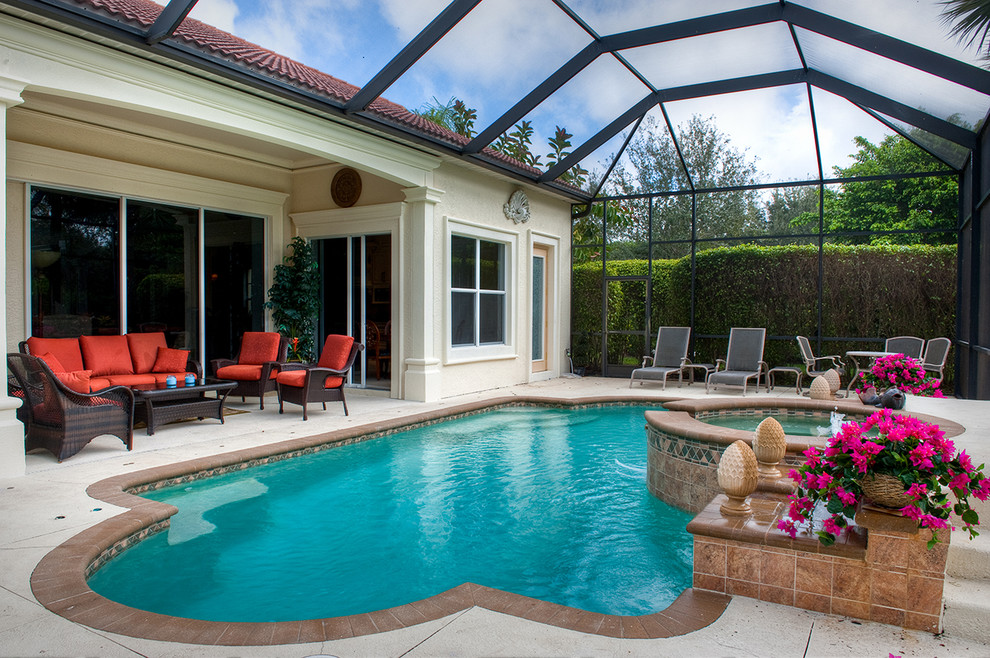 Photo of a mid-sized traditional backyard custom-shaped natural pool in Miami with a hot tub and concrete pavers.