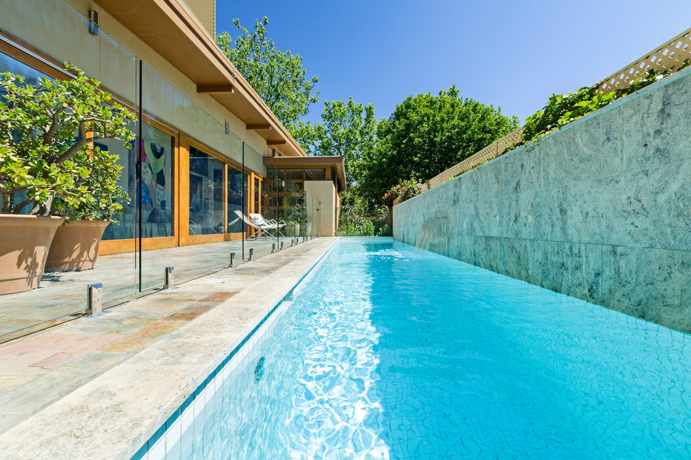 Modern side yard rectangular lap pool in Melbourne with natural stone pavers.