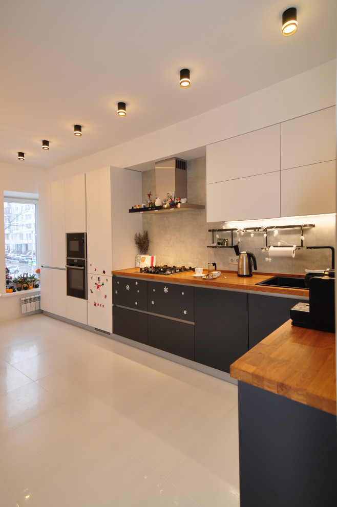 Design ideas for a large contemporary l-shaped eat-in kitchen in Other with an undermount sink, flat-panel cabinets, wood benchtops, white splashback, engineered quartz splashback, black appliances, porcelain floors, no island, white floor and beige benchtop.